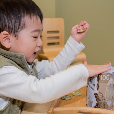 Child is Putting Coins in the Money Jar at Rothewood Academy